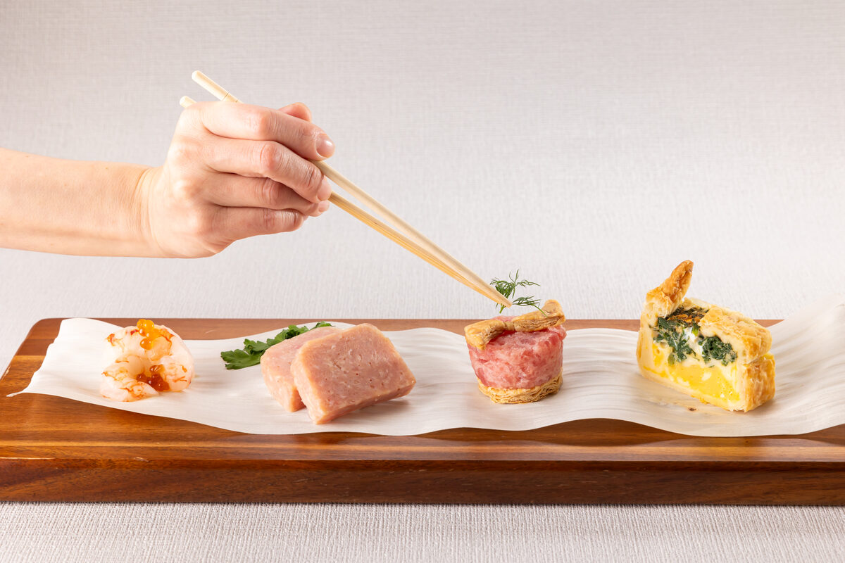 経木を敷いた皿から料理を取り分ける